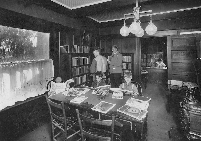 Interior of the Newark Library, 1911. This first Alameda County Library unincorporated Newark location was housed in a bungalow on Filbert Street, furnished by the Newark Development Company. Newark’s first librarian was Mabel Fowler Callow. She is seen here working at her desk in the back room. (Newark)