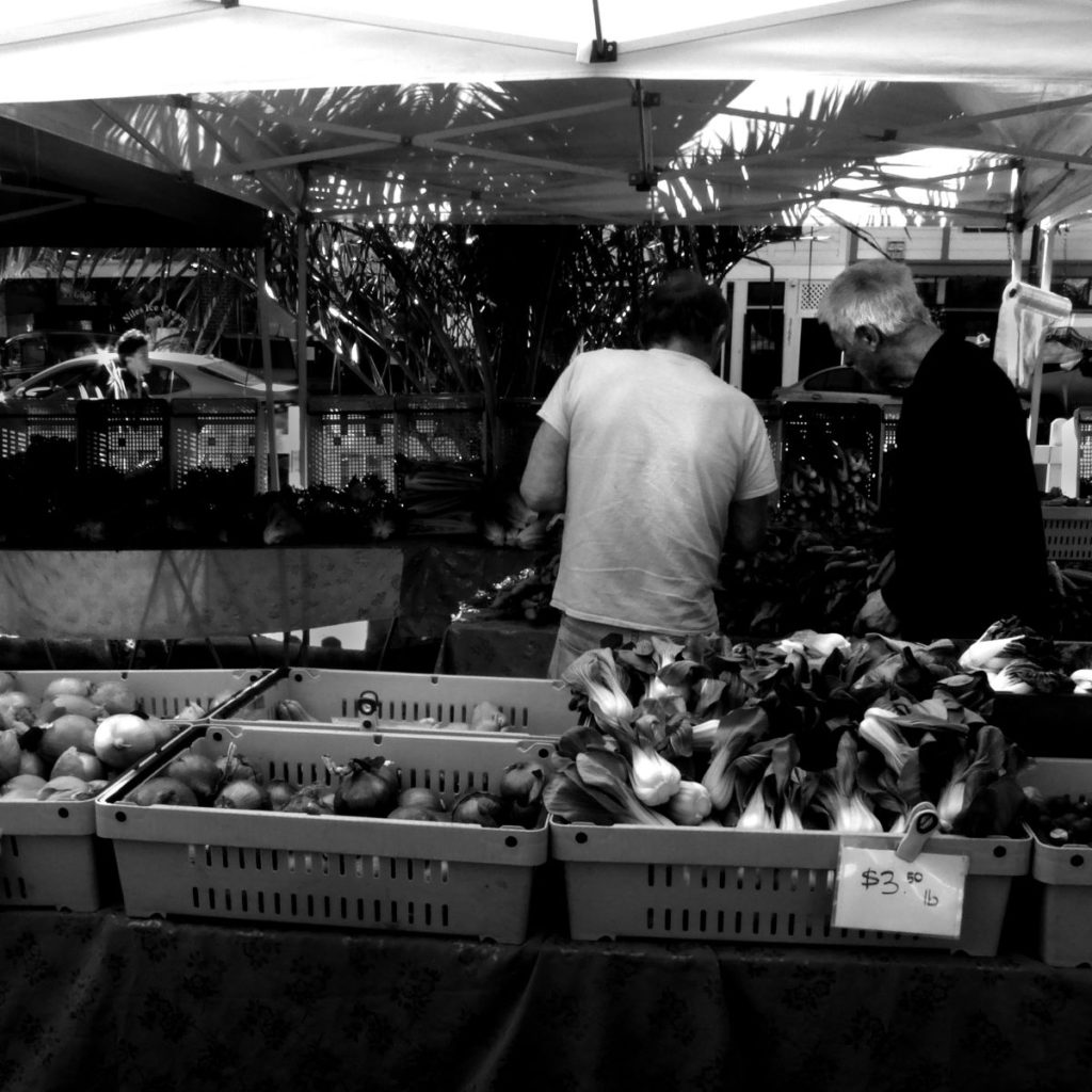 At the Niles Farmers Market, also in Fremont, a couple hauls heavy bags back to their car; two men decide among carrots.