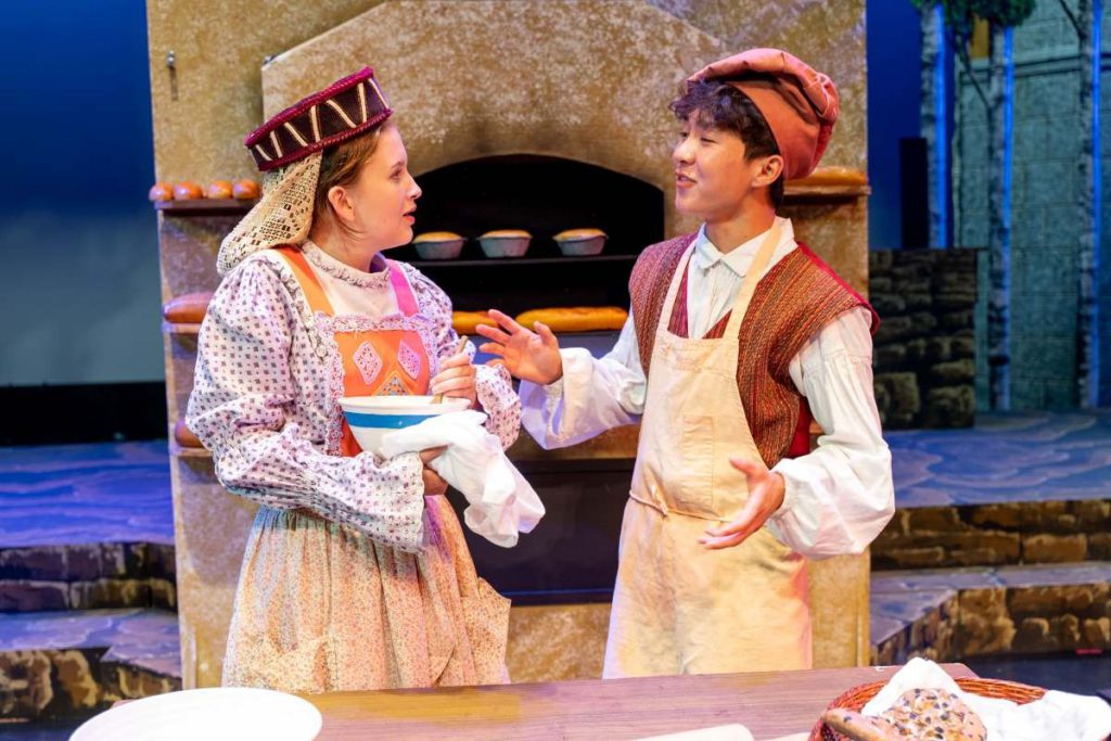 Sydney Walker Freeman as the Baker’s Wife and Russell Lym as the Baker wish to start cooking another type of bun in the oven. Kae-Chy Chang