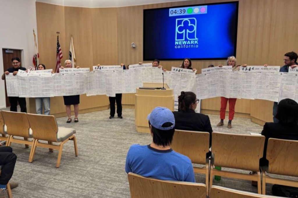  coalition of environmental groups including Citizens Committee to Complete the Refuge and Greenbelt Alliance hold up a large banner of petition signatures at a Newark City Council meeting on Oct. 23.
Roelle Balan.