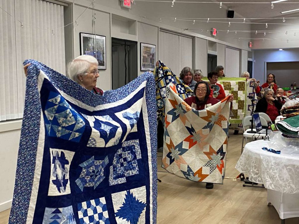 At the Dec. 2025 meeting, the guild donated dozens of quilts to local organizations while the makers paraded the quilts around the room to be admired. Stephanie Uchida