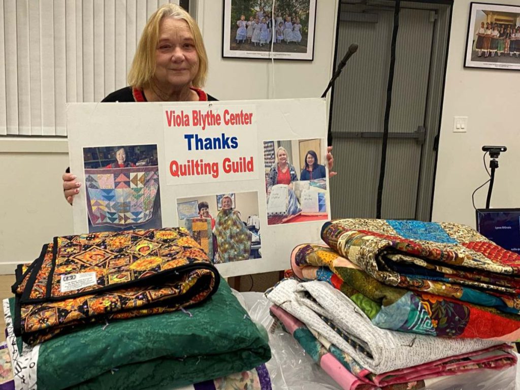 Debra Rodriguez, executive director of Viola Blythe, accepts a stack of quilts for the nonprofit. Stephanie Uchida